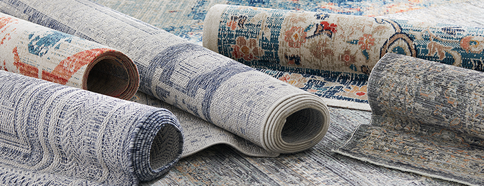 Rolled rugs with intricate patterns arranged on a surface.