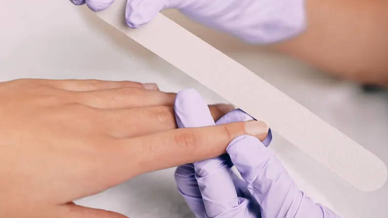 Professional manicurist filing a nail. 