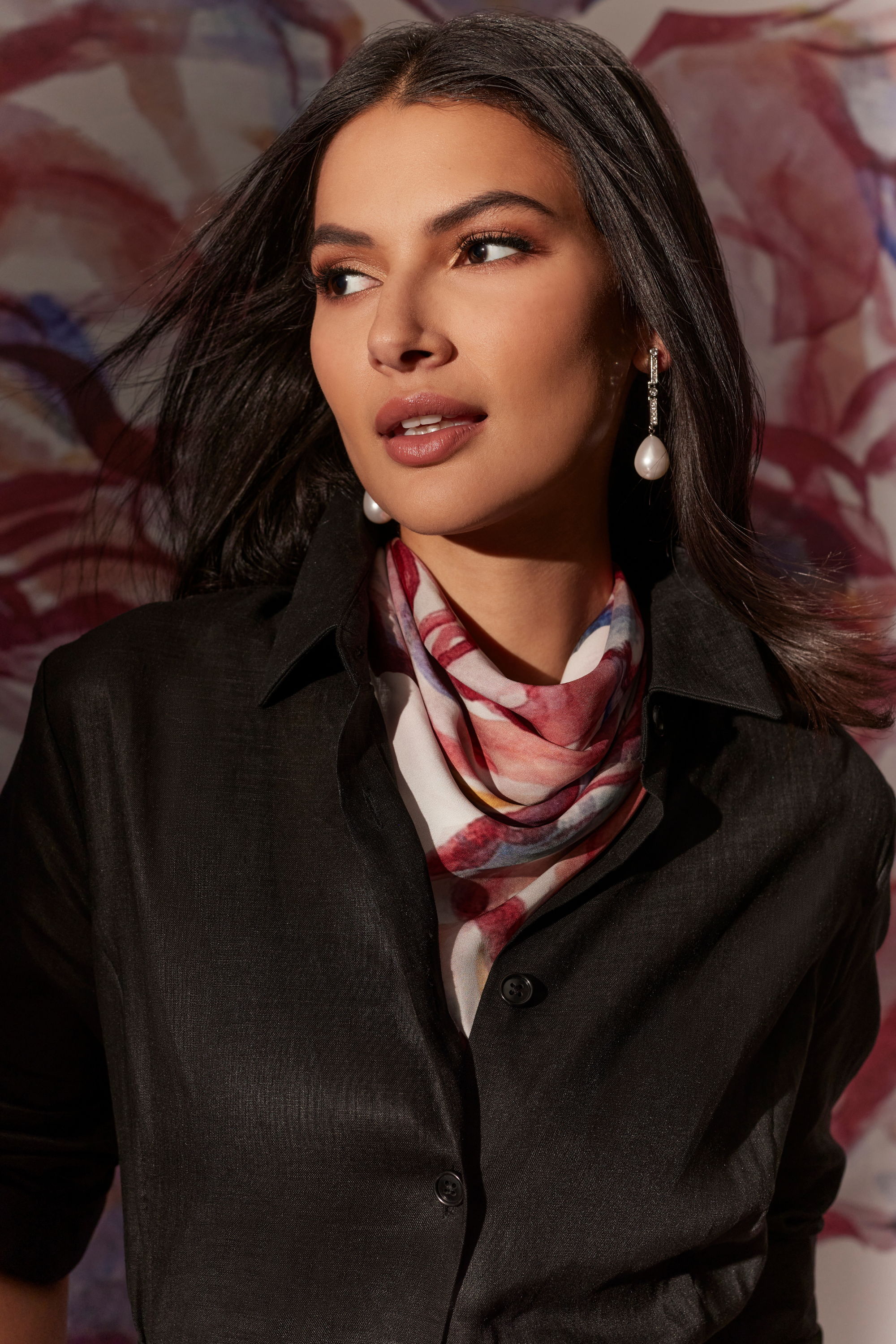Woman wearing a scarf and earrings, with a soft background.