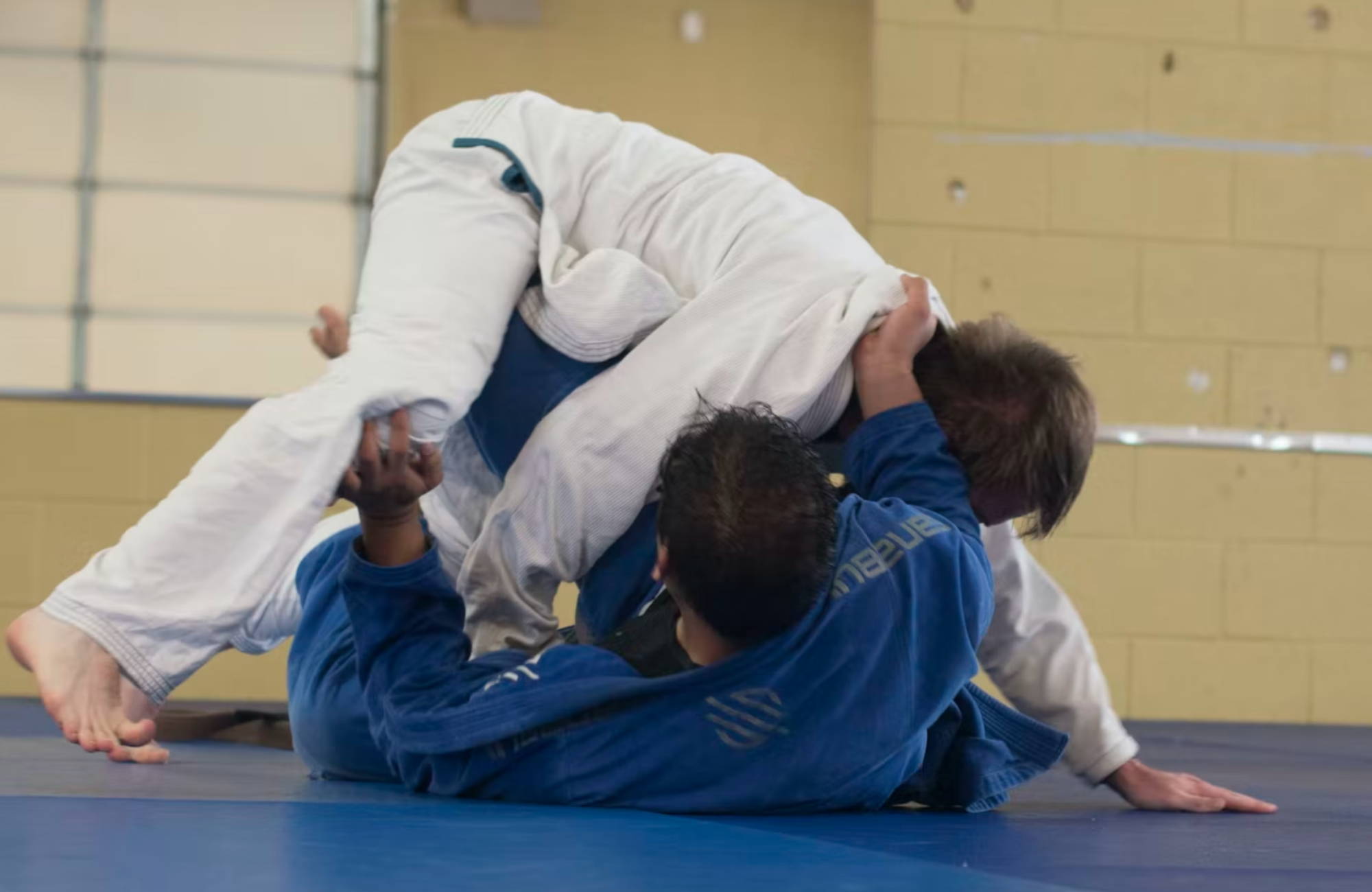  two men, one in a white gi and the other in a blue gi, grappling