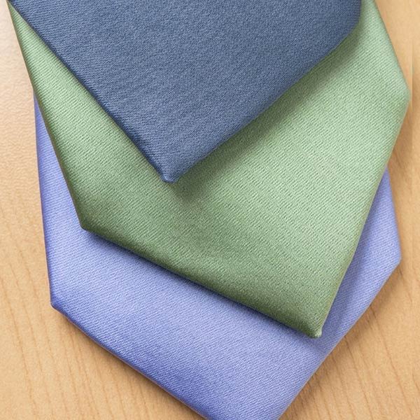 Closeup of solid color ties in dusty blue, sage and periwinkle