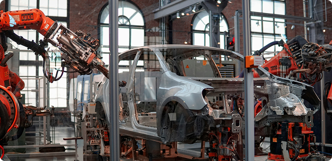 Robotic arms assembling a car in a modern factory setting.