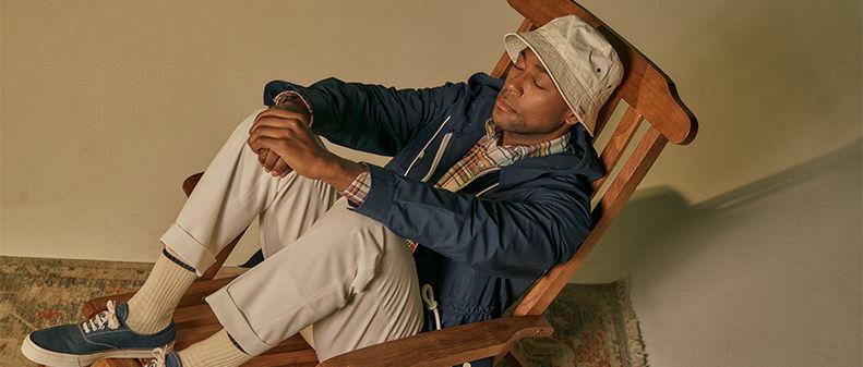 Person sitting in a rocking chair, wearing a hat and casual clothing.