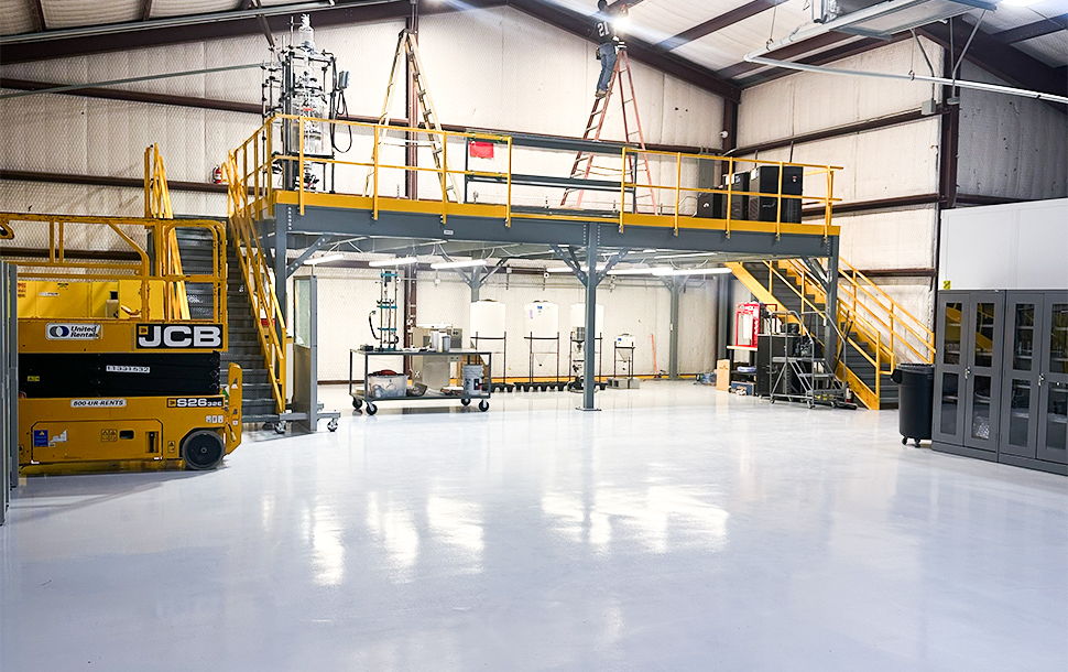 Interior view of a spacious industrial workshop with yellow stairs and machinery.