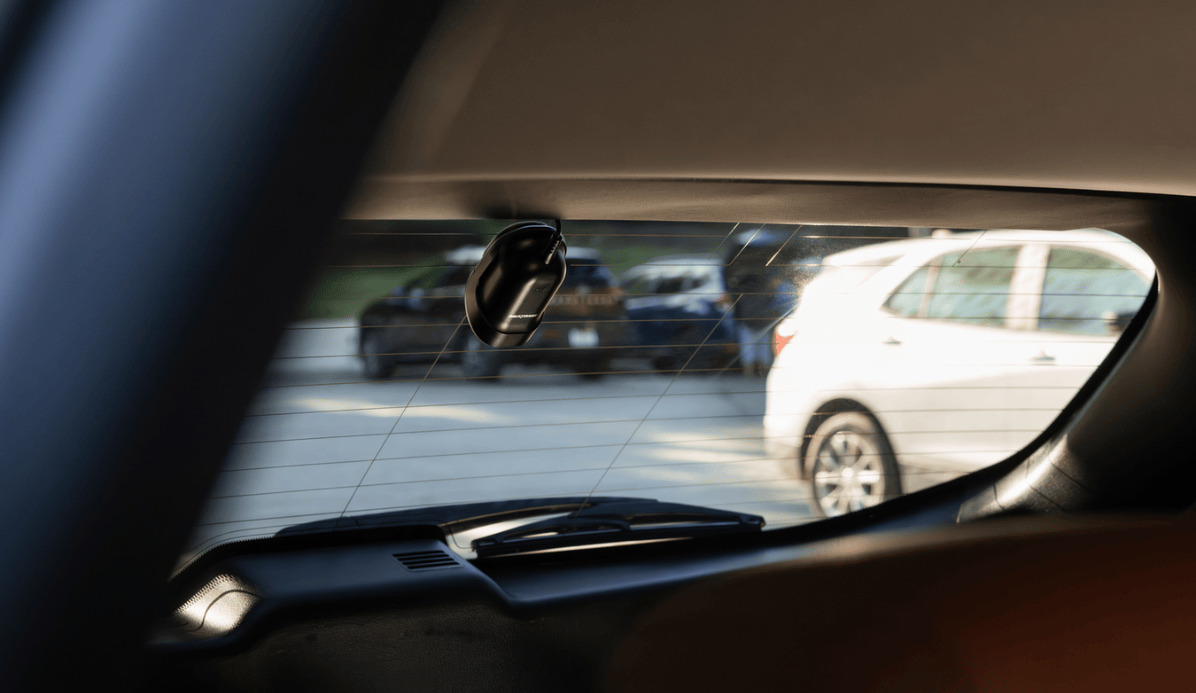 View of parked cars through a vehicle's rear window.