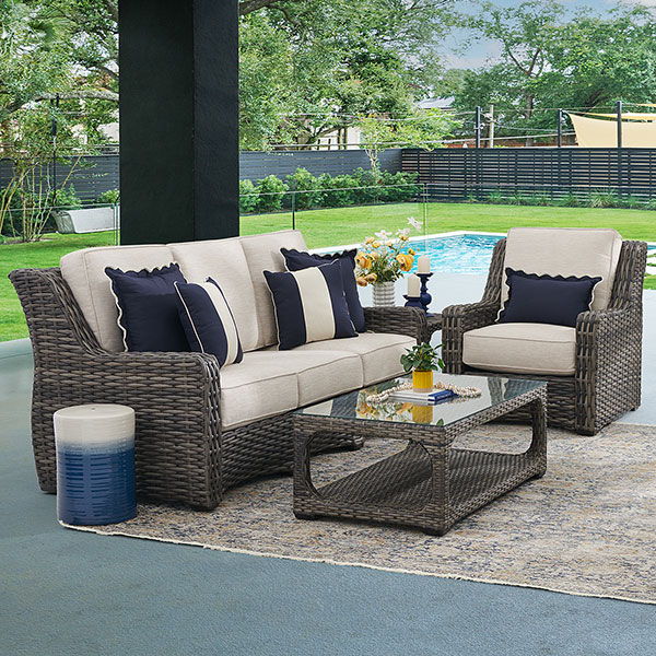 Outdoor seating area with a sofa, chairs, and a coffee table by a pool.