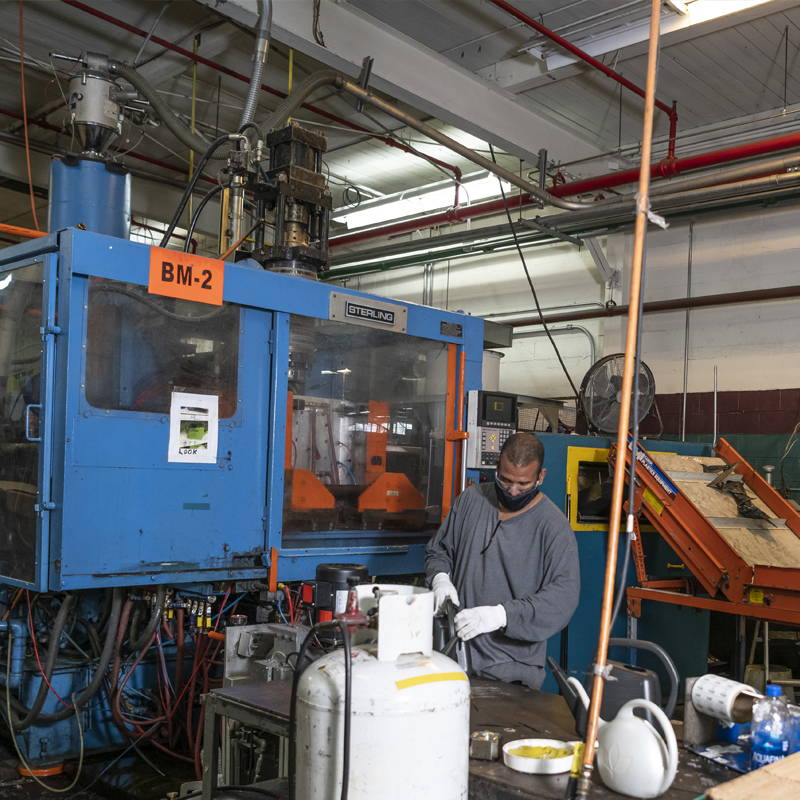 Employee working a blow molding machine