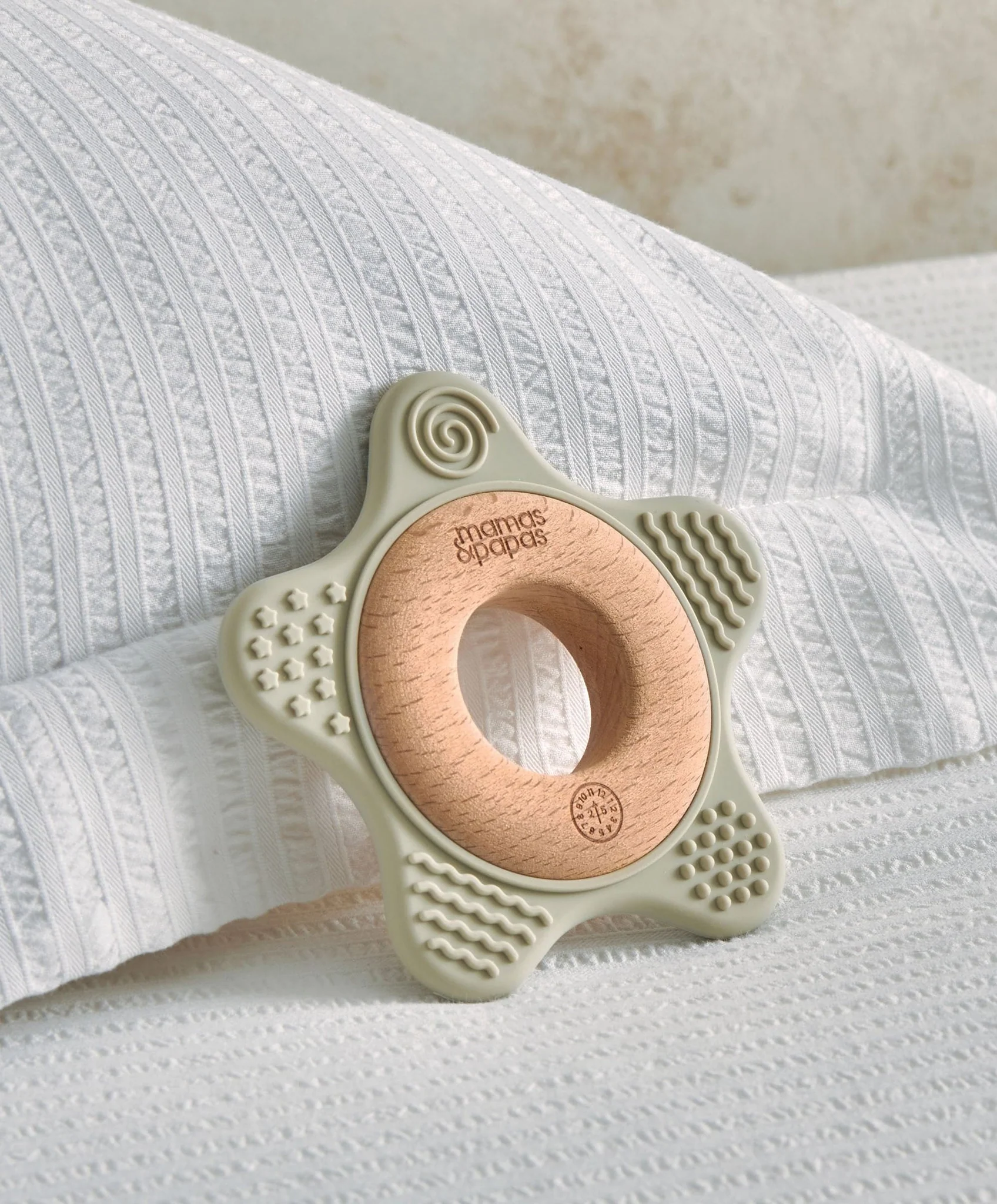 Star-shaped teething toy resting on a textured white pillow.