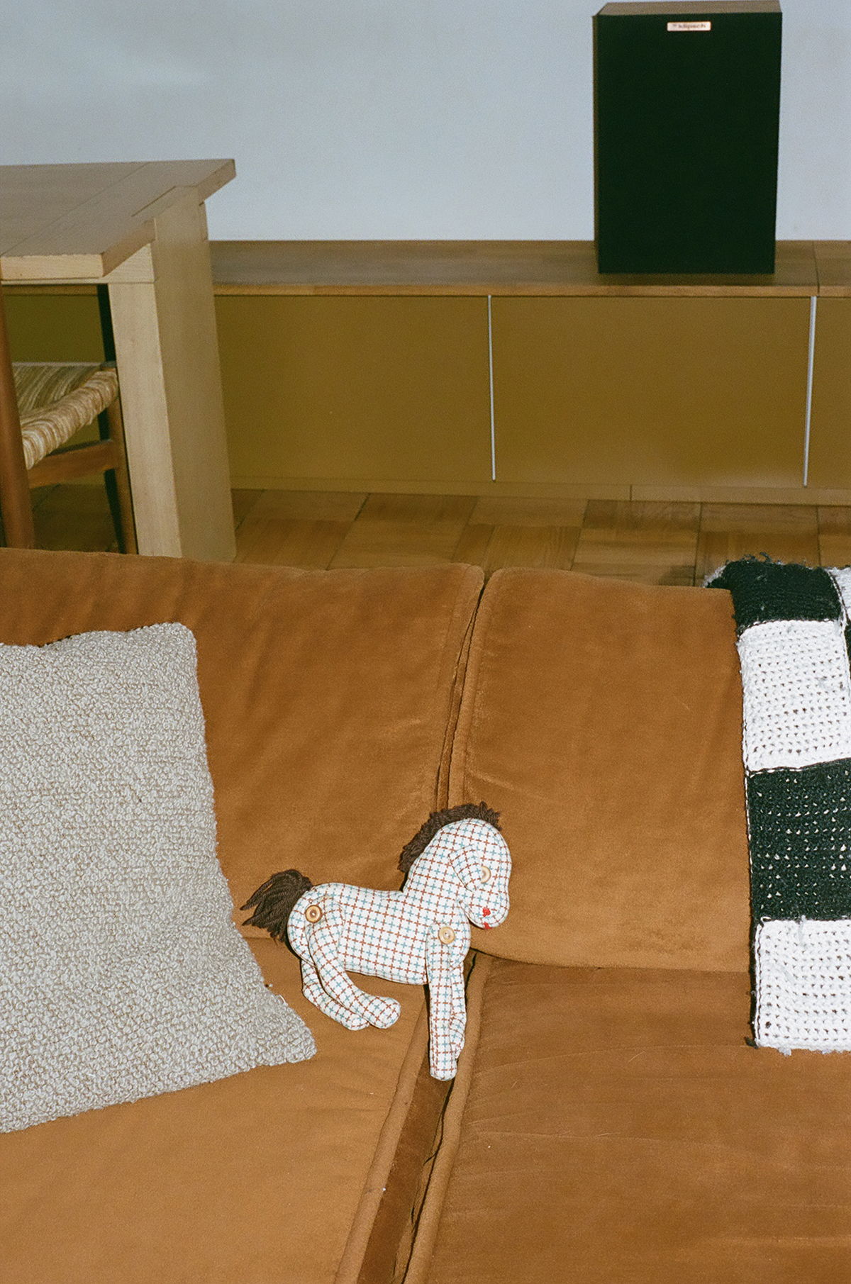 A cozy living room with a plush horse toy on a brown couch.