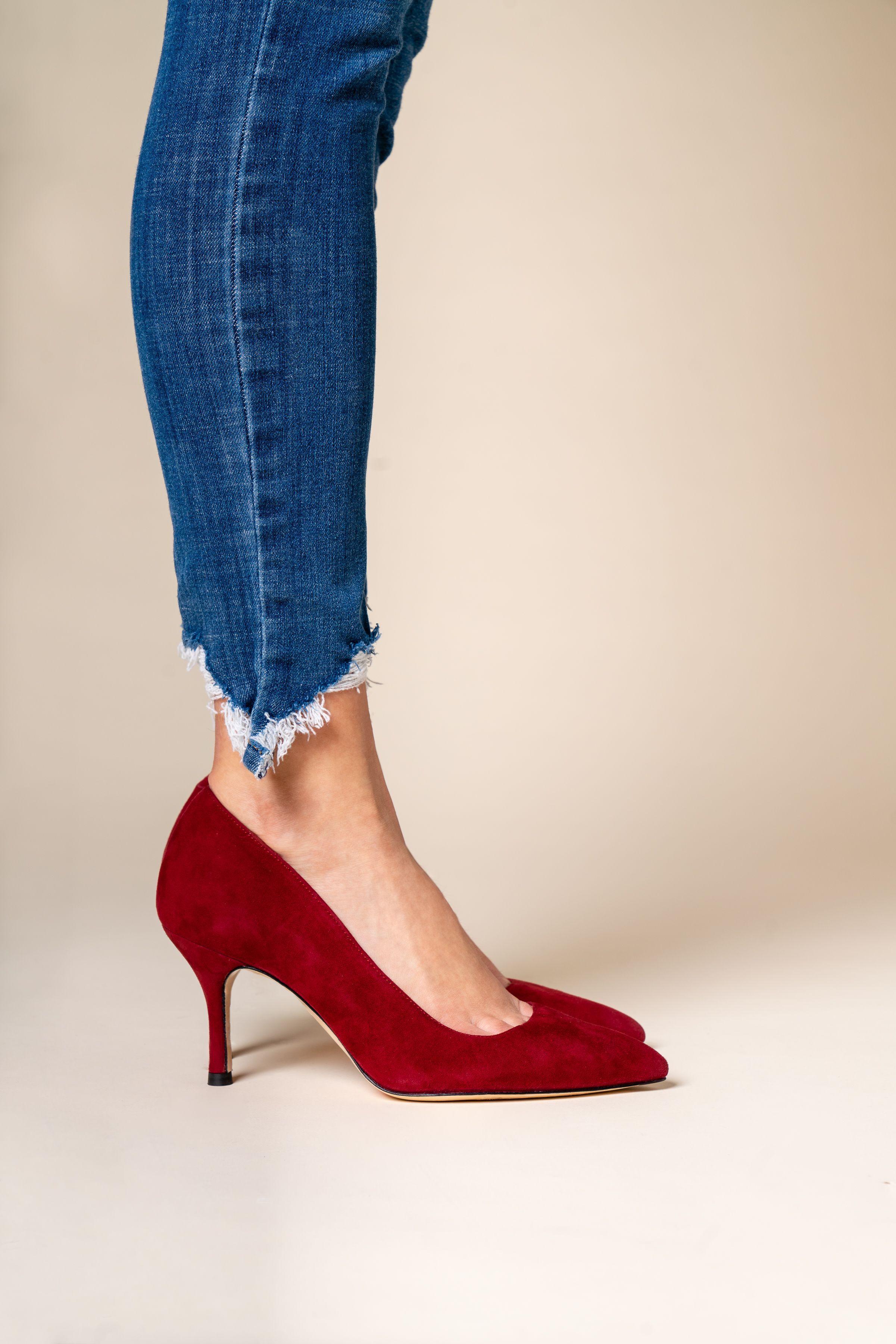 Woman's foot in red high heel shoe next to denim jeans.