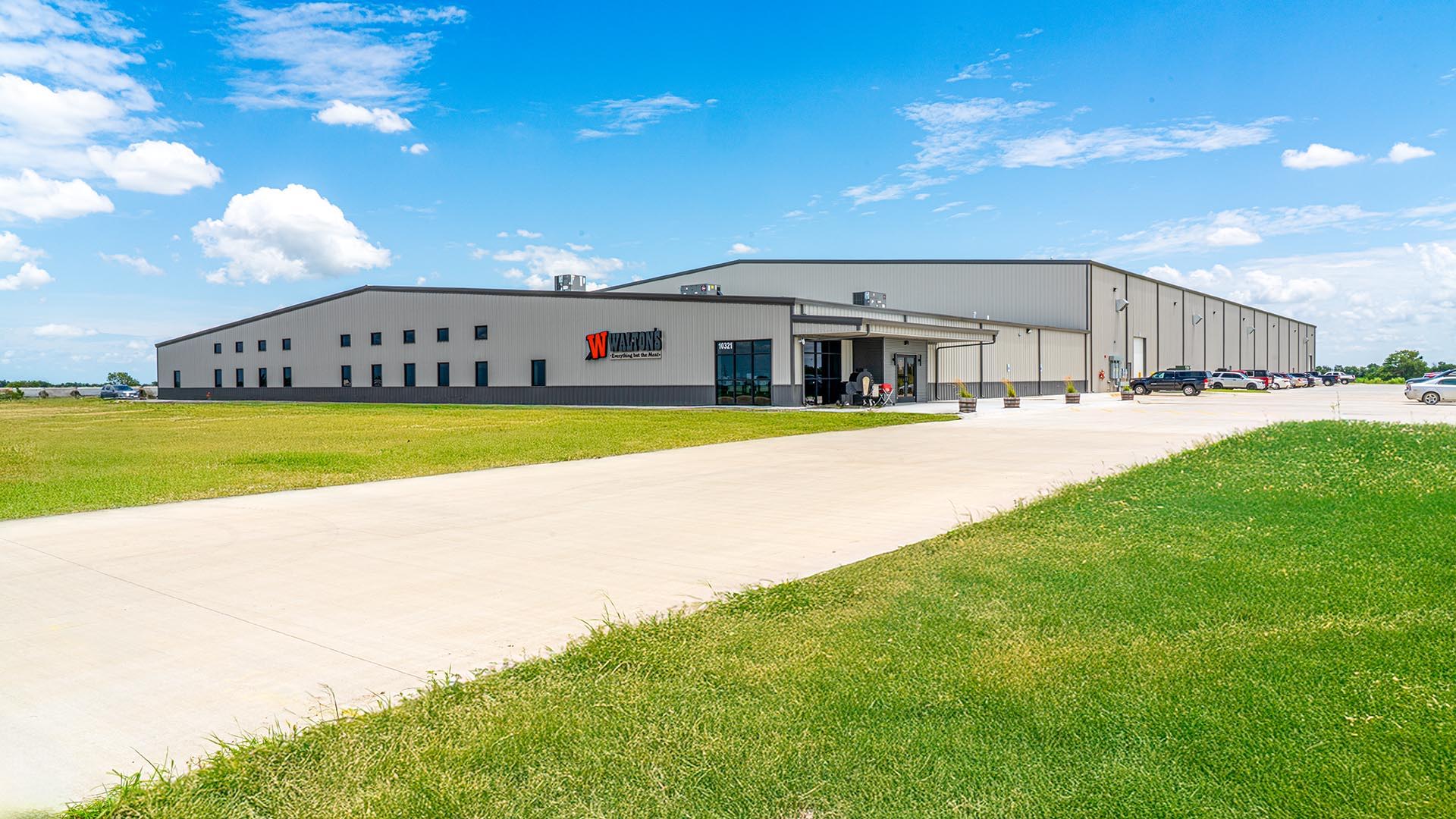 Walton's building with a clear blue sky and green grass.