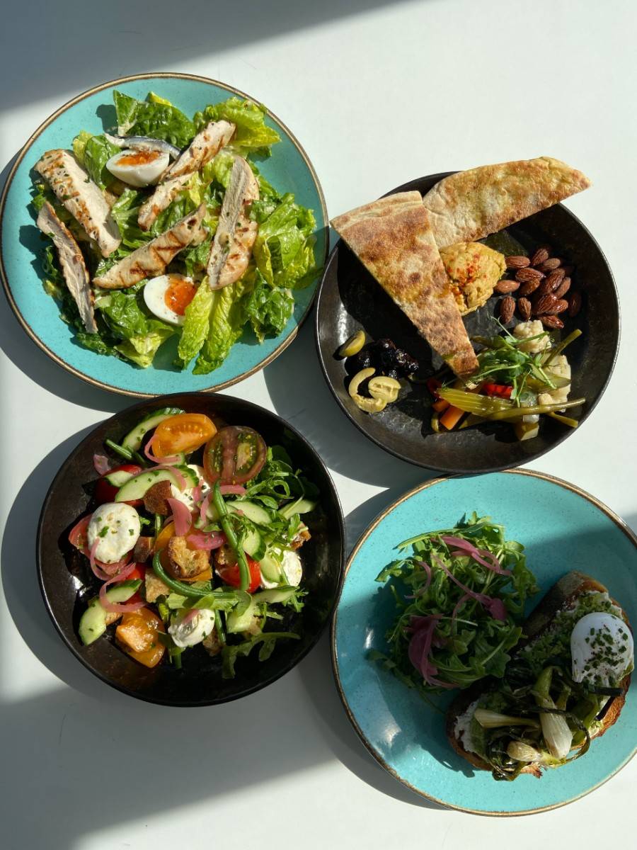 Four plates of salads and mezze on a table in the sunshine at The Factory Kitchen cafe in Newcastle