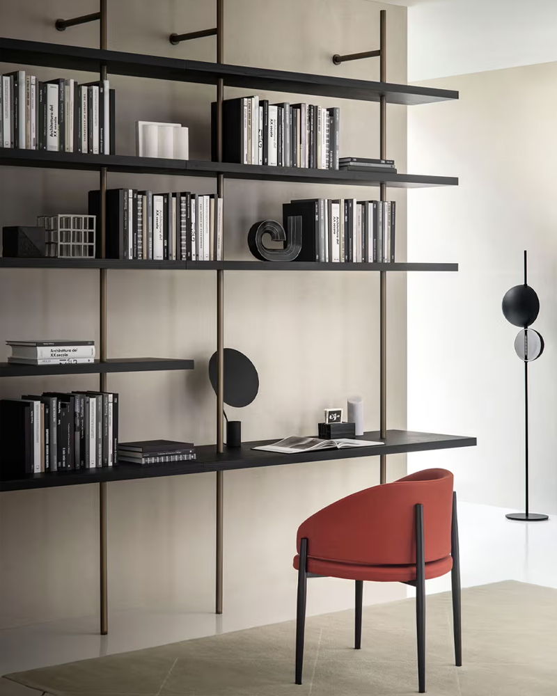 Modern Porro interior fitted furniture with shelves, books, and a red chair.