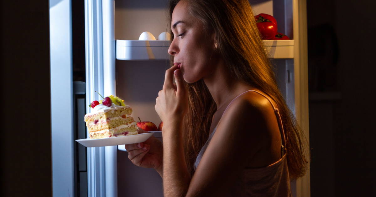 A woman enjoys a late-night treat from the fridge.
