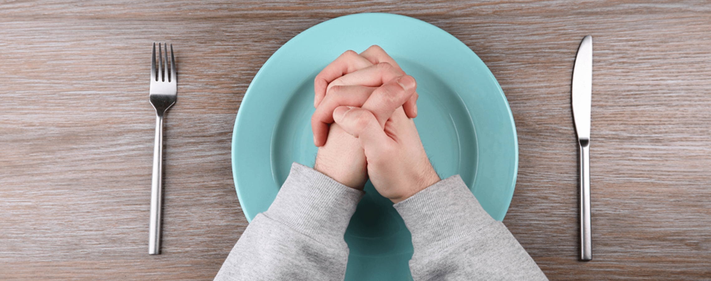 Boy clasping hands over empty plate