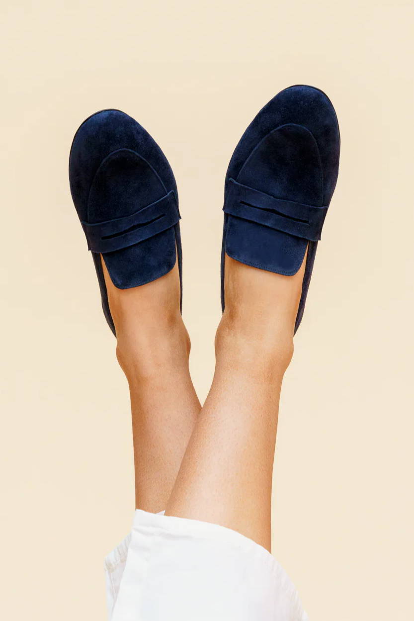 A pair of feet wearing navy shoes against a light background.
