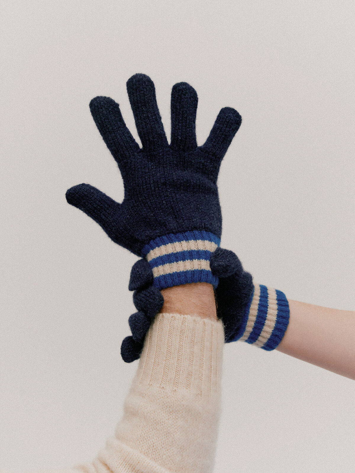A look book image of a model's hands wearing a pair of navy Howlin' gloves.
