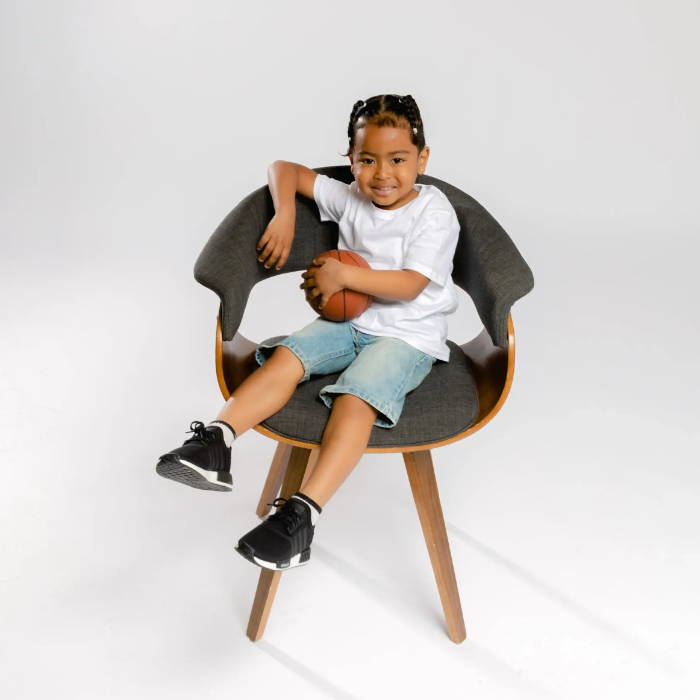young boy sitting on chair wearing adidas shoes