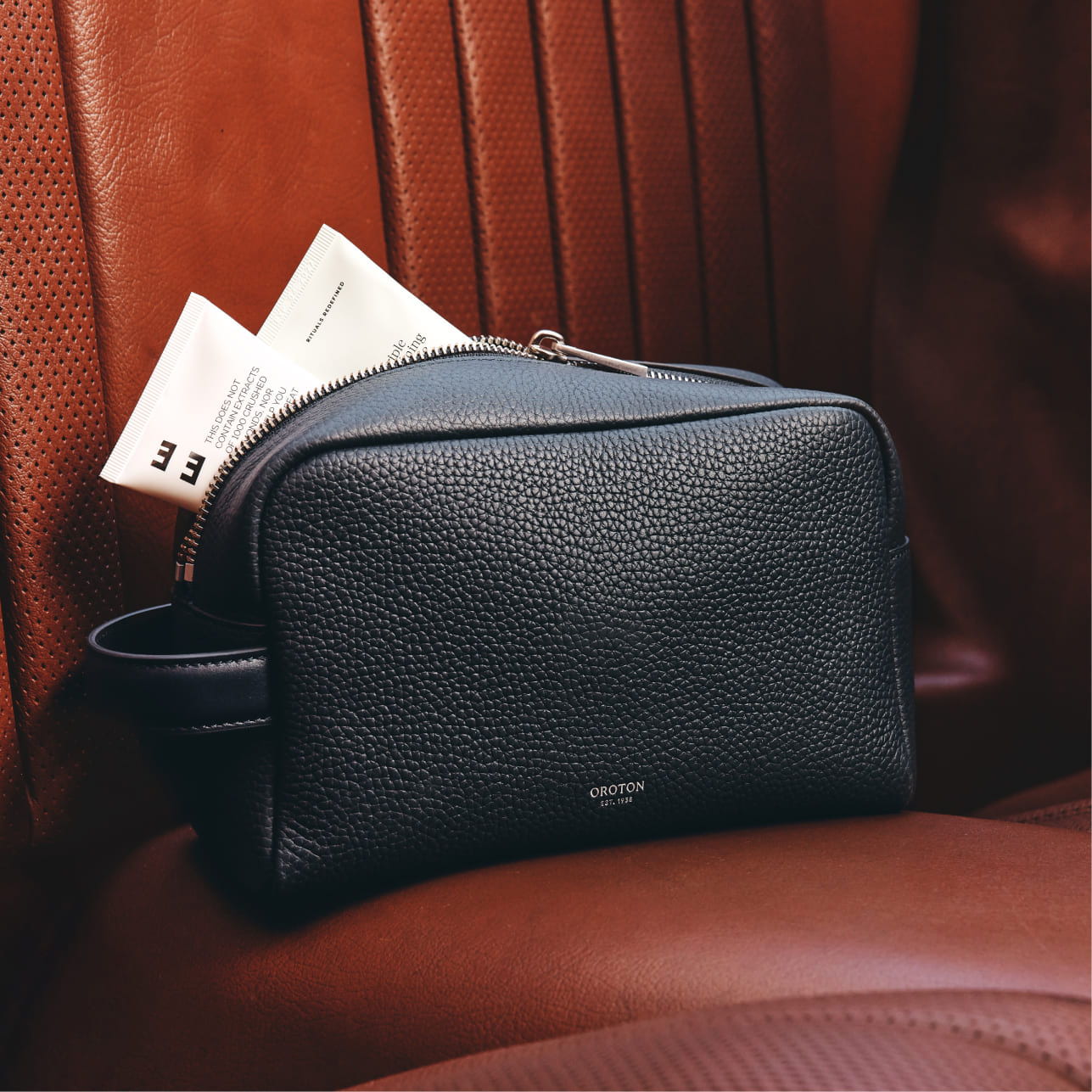 Black leather bag on a brown leather seat with papers inside.