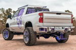Rear driver-side view Ismael's lifted Silverado with purple skull decal and chrome wheels photo 3