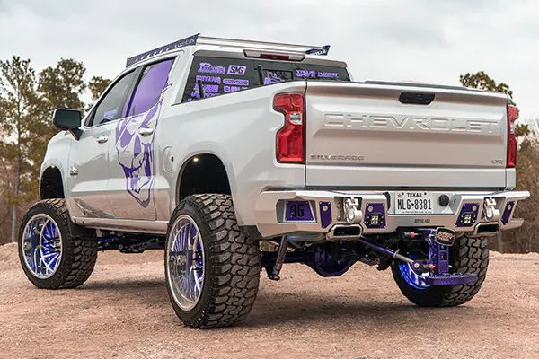 Rear driver-side view Ismael's lifted Silverado with purple skull decal and chrome wheels photo 3