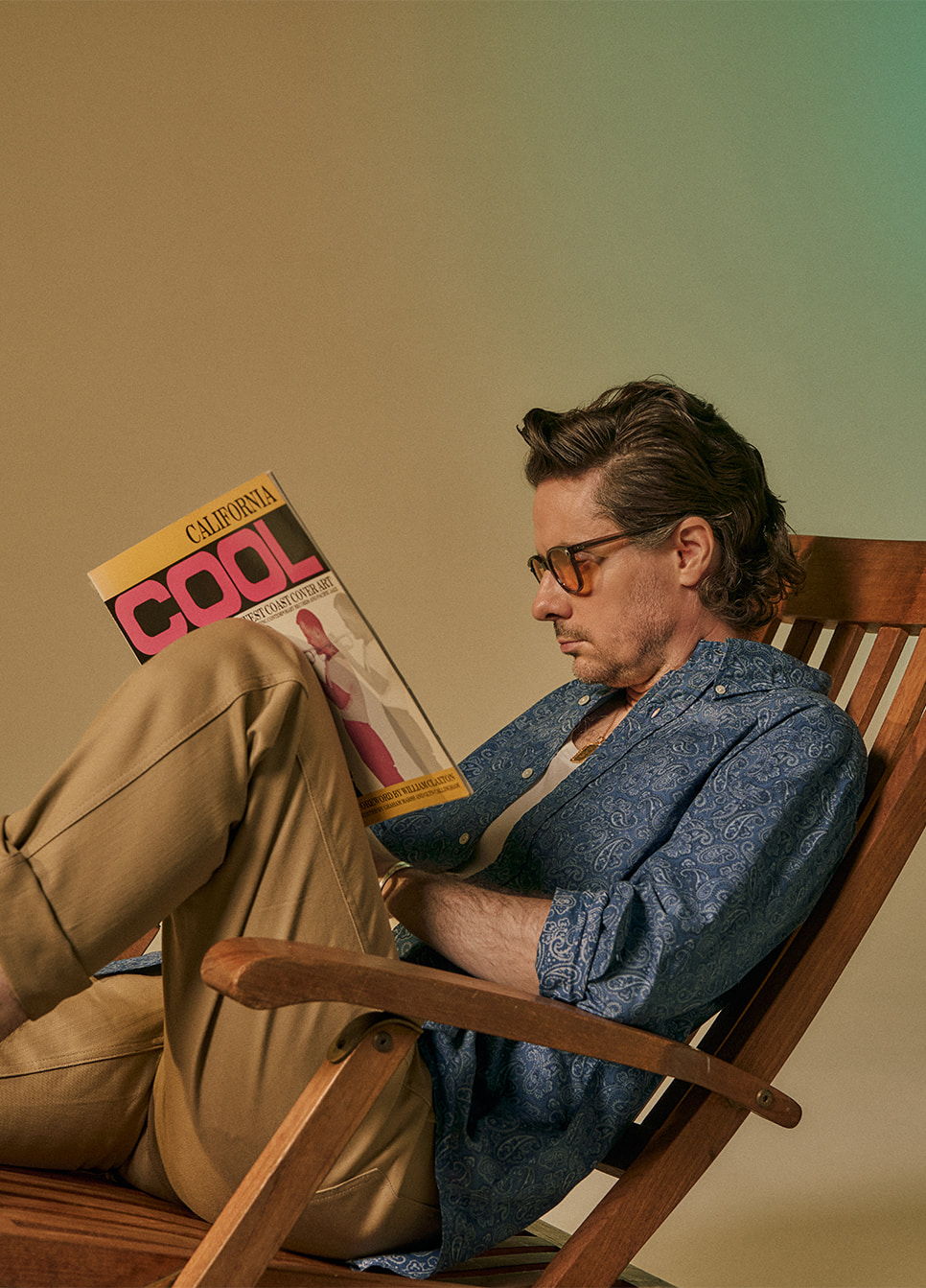 Person reading a magazine while sitting in a rocking chair.
