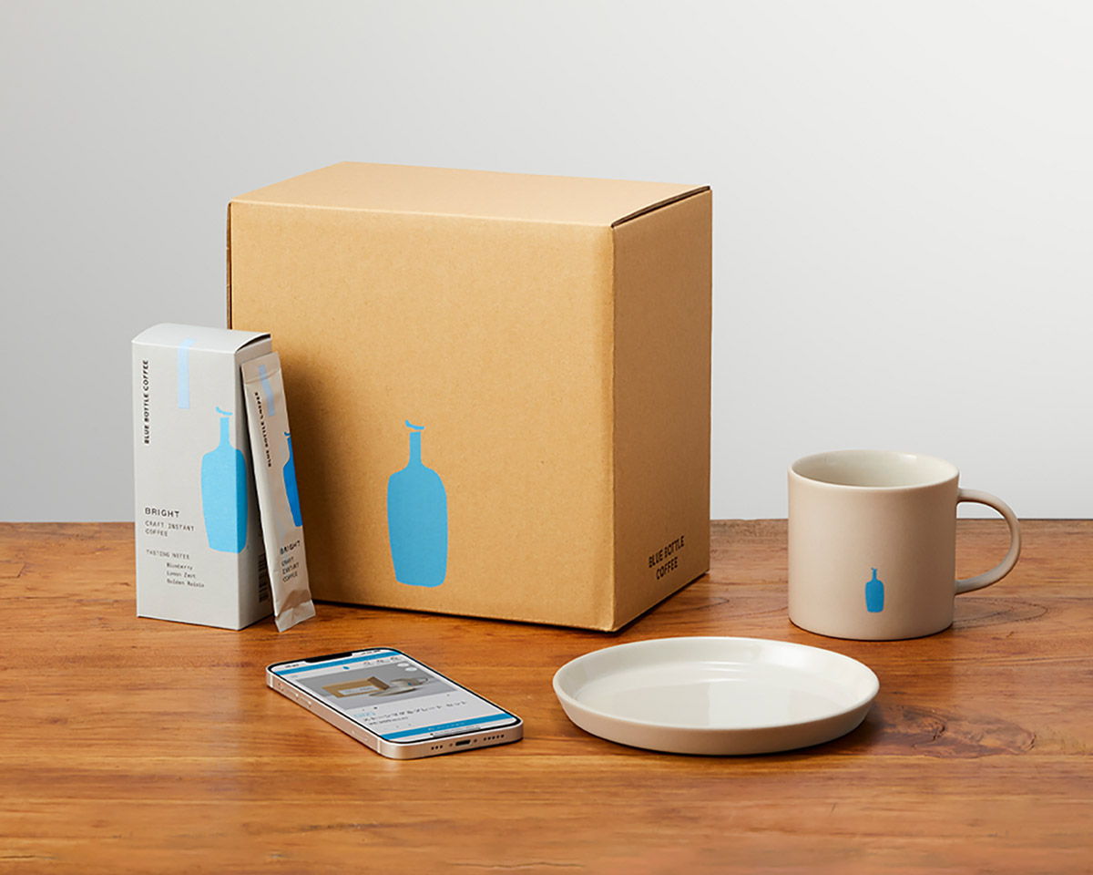 Coffee package, mug, plate, and box on a wooden table.