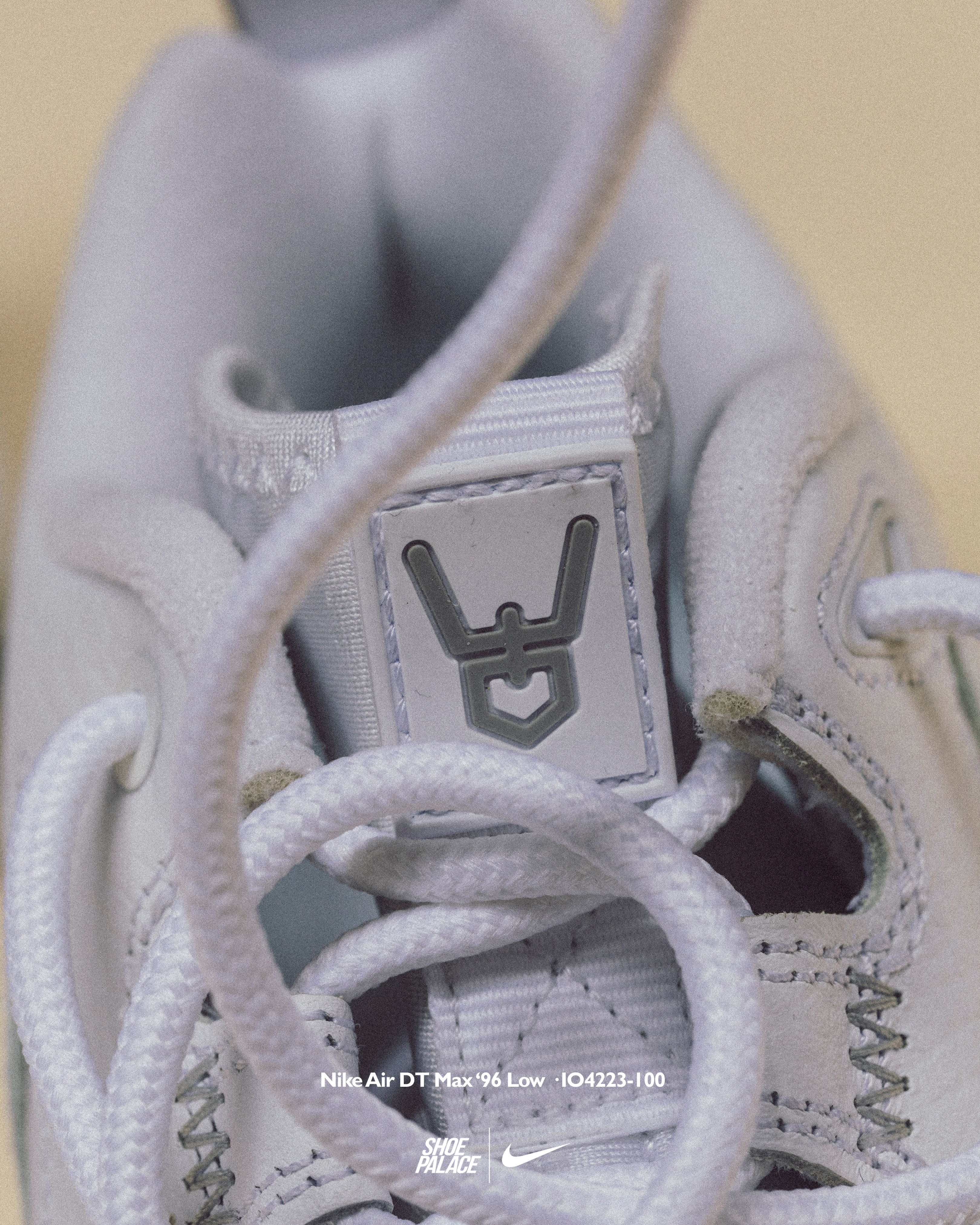 Close-up of a white sneaker with a logo and laces.