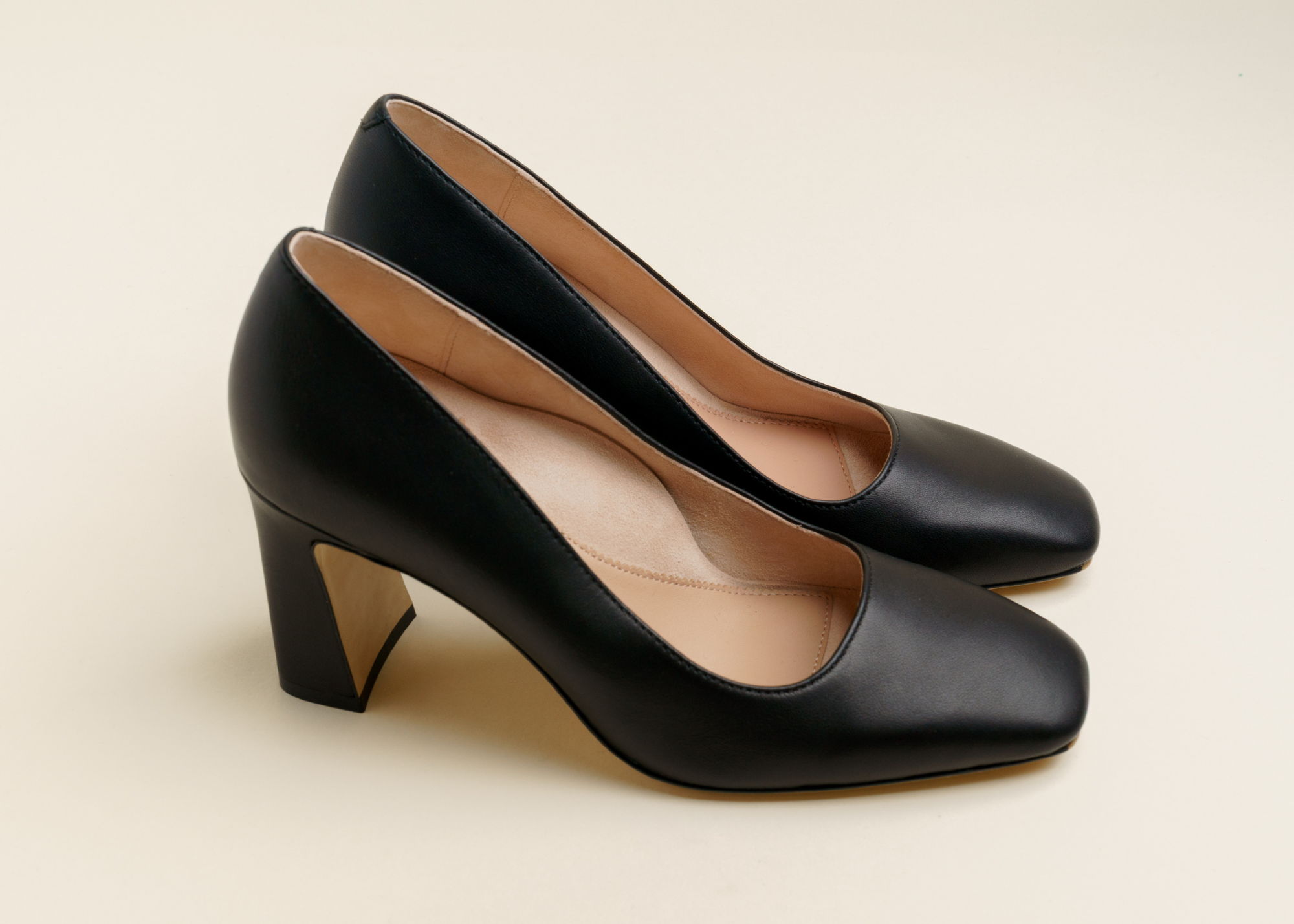 A pair of black high heels on a neutral background.