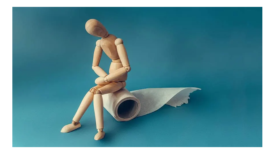 wooden art person sitting on roll of toilet paper