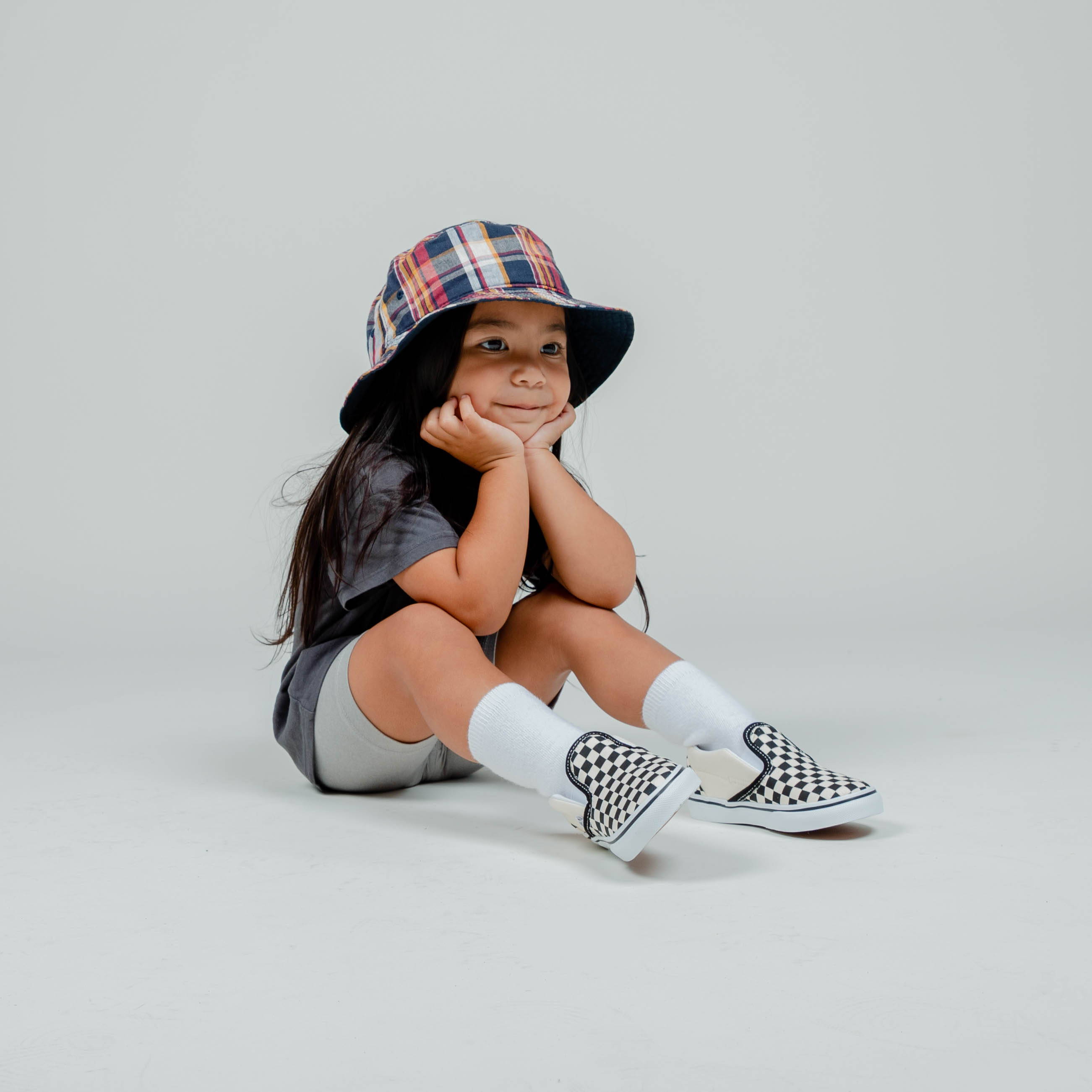 young girl sitting on floor wearing checkered vans