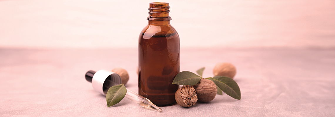 Brown glass bottle with a dropper, surrounded by nuts and leaves.