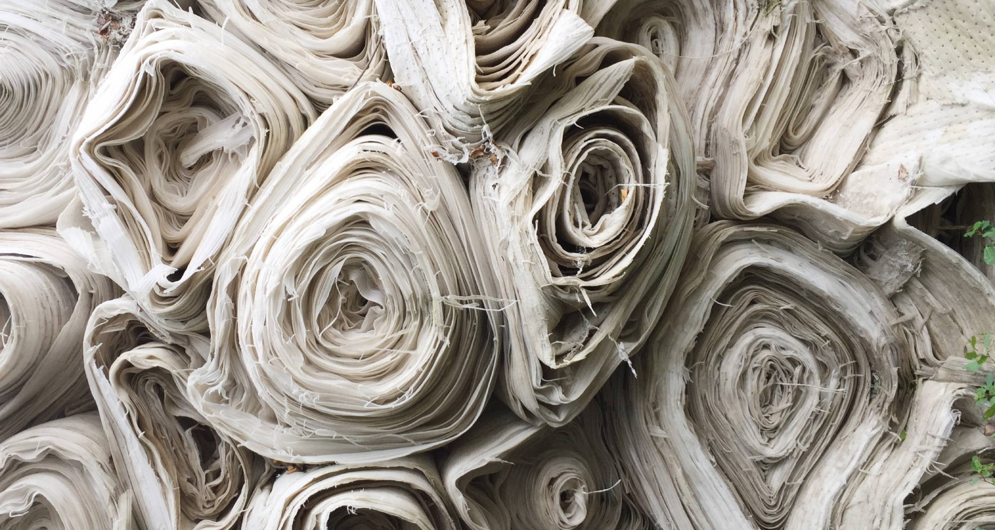 Rolls of white fabric sit stacked against one another.