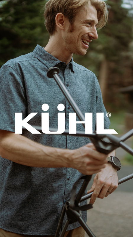 Man smiling while assembling outdoor gear, wearing a button-up shirt.