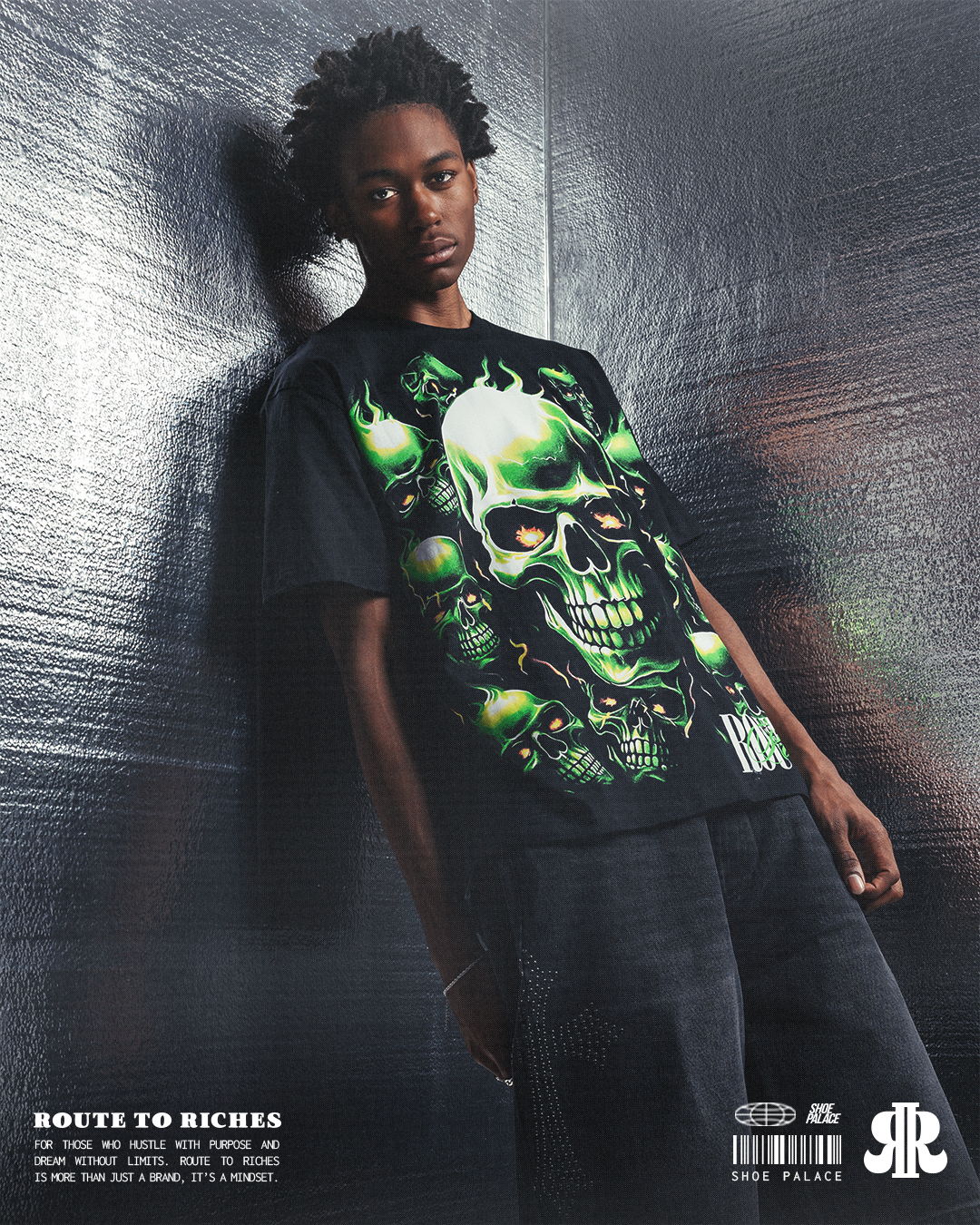 Young man wearing a skull graphic t-shirt, leaning against a wall.