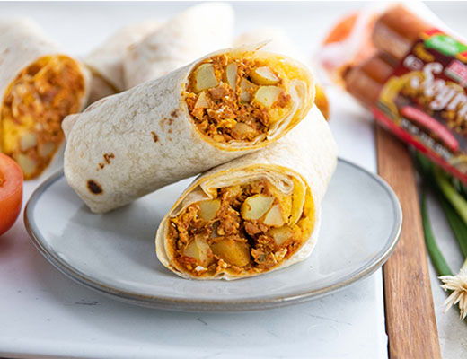 Plate of potato and soyrizo burritos sliced in half on a wooden surface.