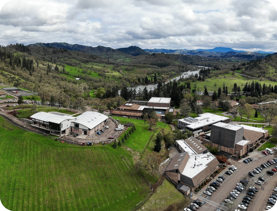 Aerial view of a campus surrounded by green hills and a river.