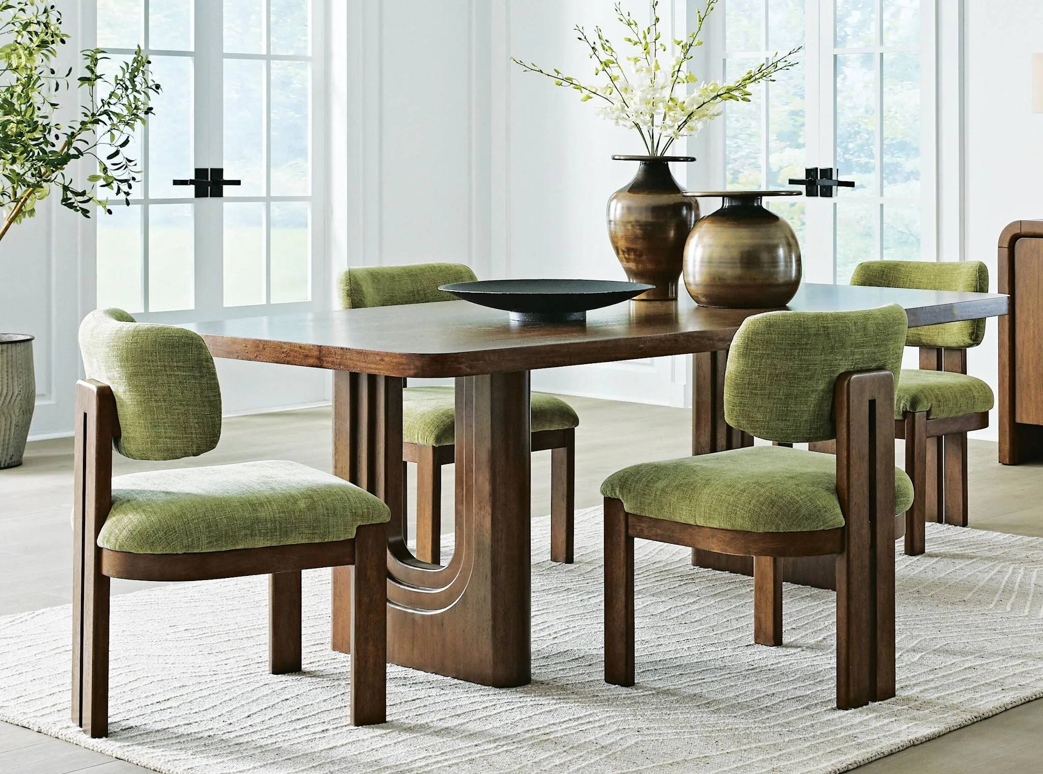 Modern dining table with green upholstered chairs and decorative vases.