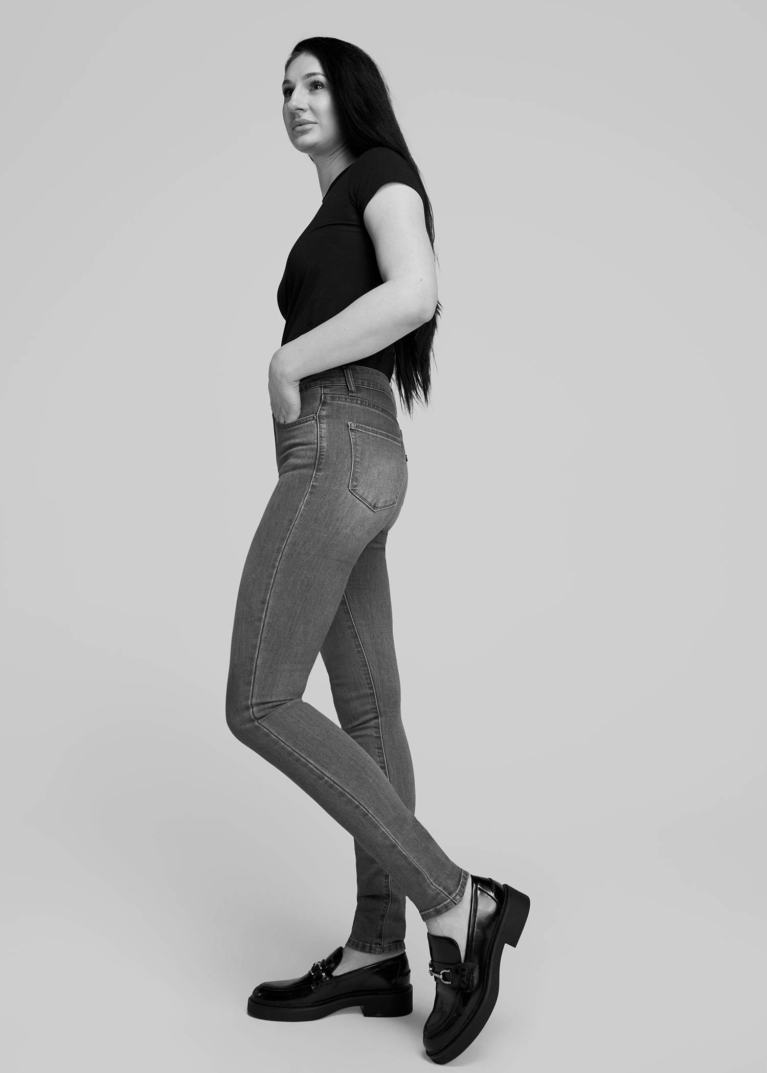A tall woman wearing a black tee adn dark washed skinny jeans