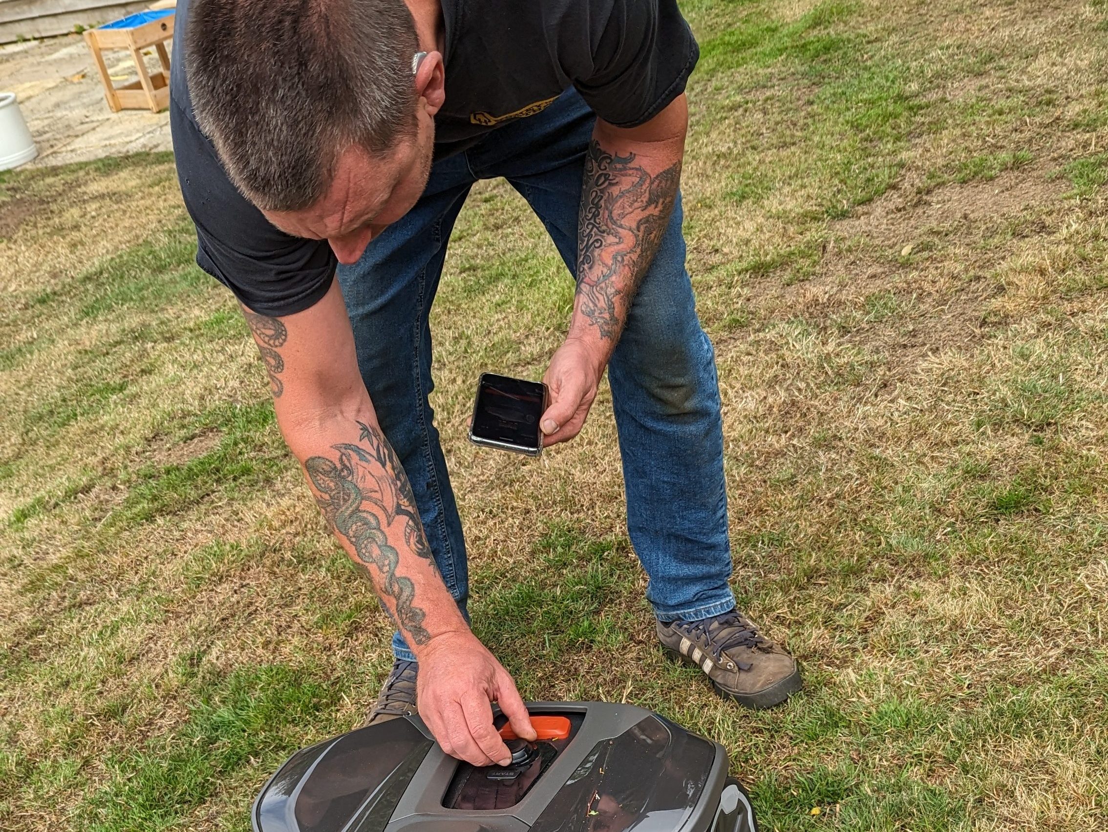 Person adjusting a device on the ground outdoors.