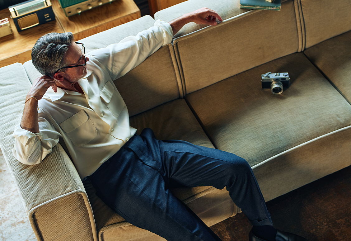 A man sitting on a couch with a camera nearby.