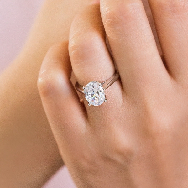 two tone engagement ring with oval cut diamond and a hidden halo of accenting diamonds