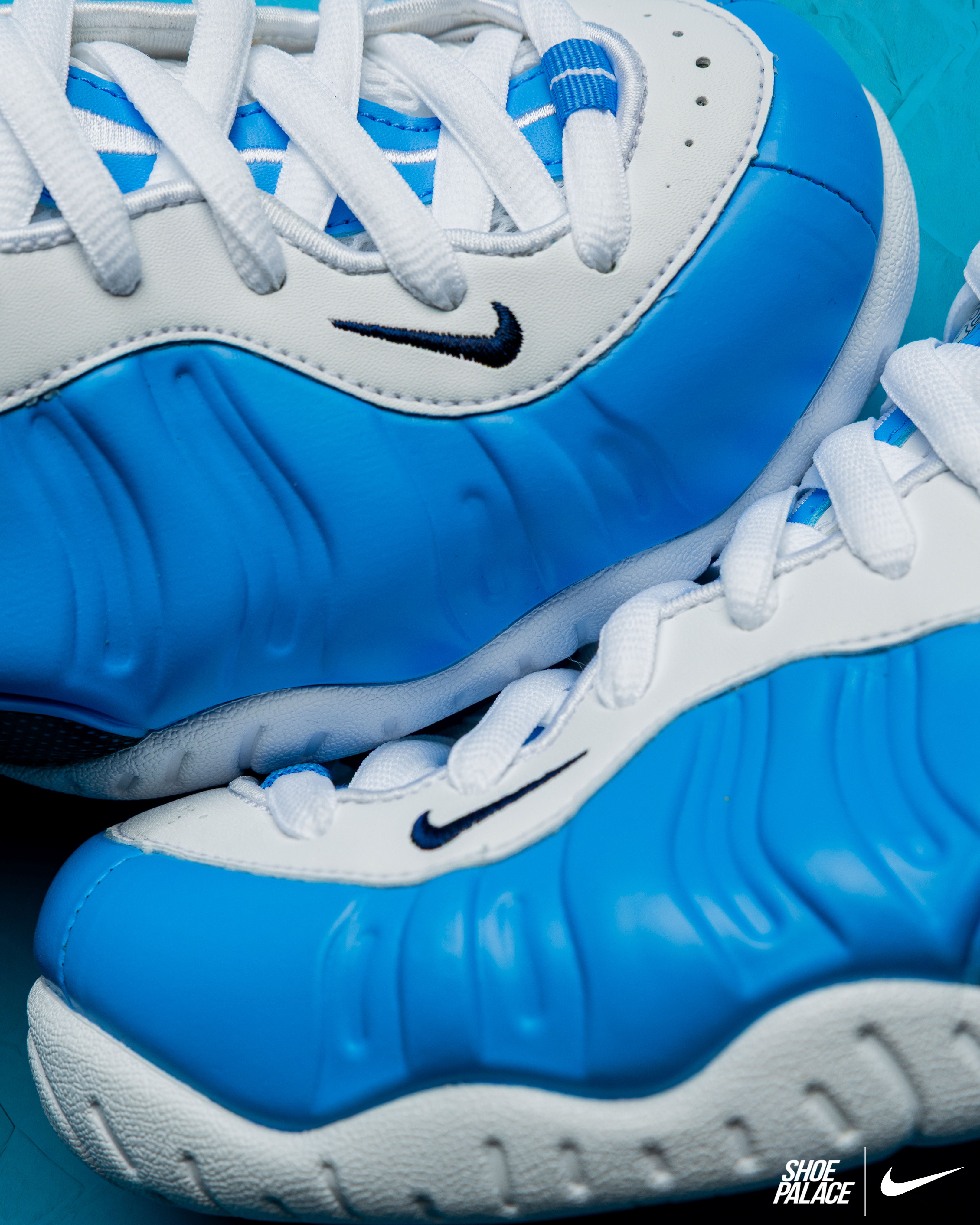 Blue and white Nike shoes on a teal background.