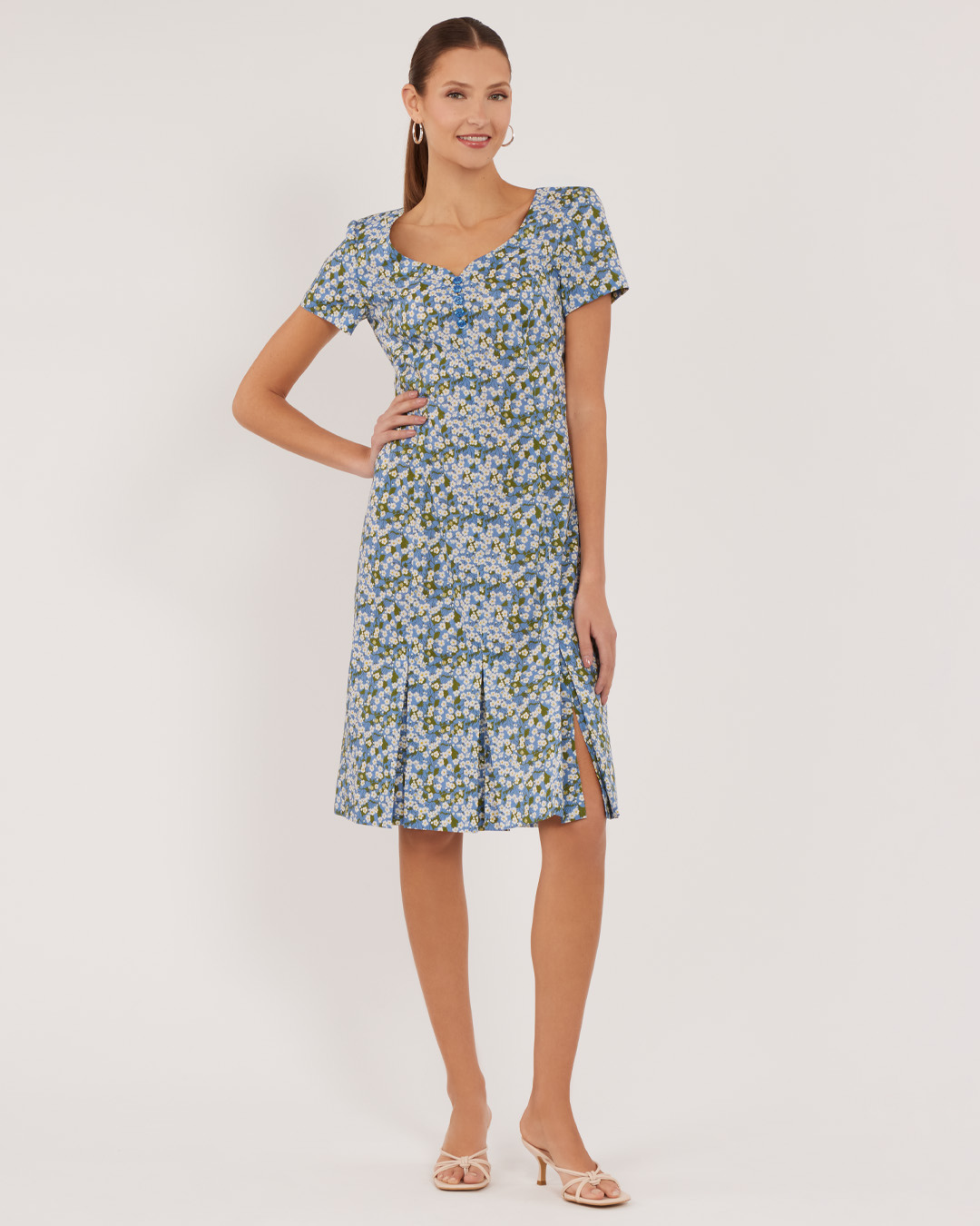 Woman wearing a floral dress with short sleeves and a flared skirt.