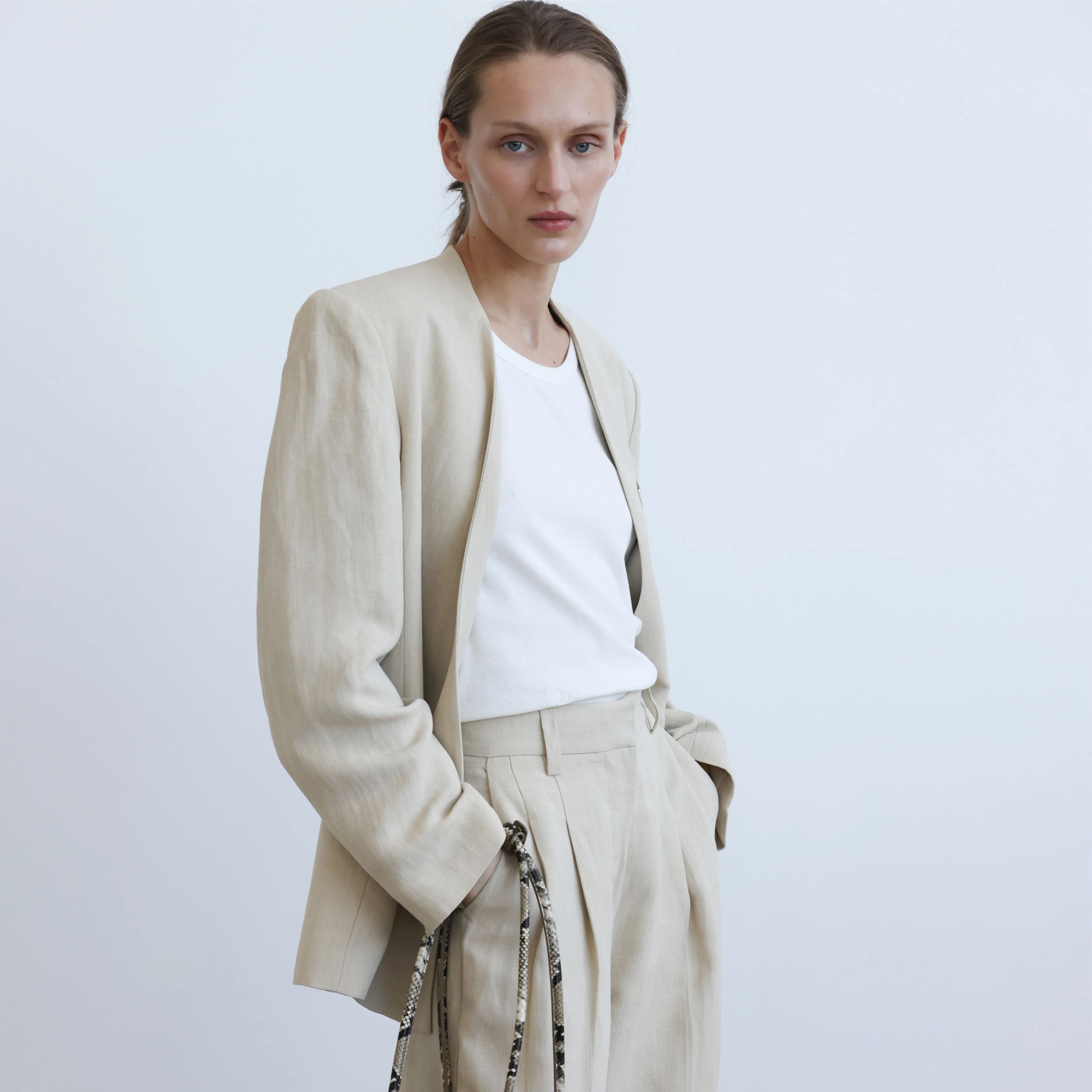 Model wearing a beige blazer and trousers against a plain background.