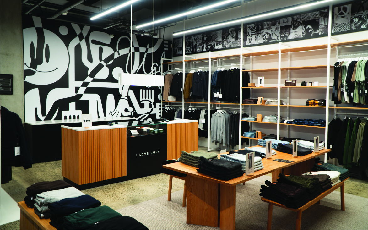 Clothing store interior with wooden displays and abstract wall art.
