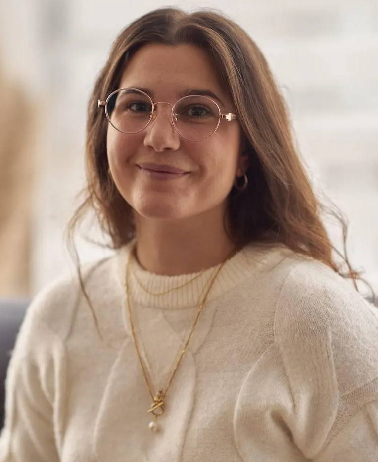 Woman with small face wearing Joy Rose Gold, Round Eyeglasses in Rose Gold Metal with a white sweater and gold necklace