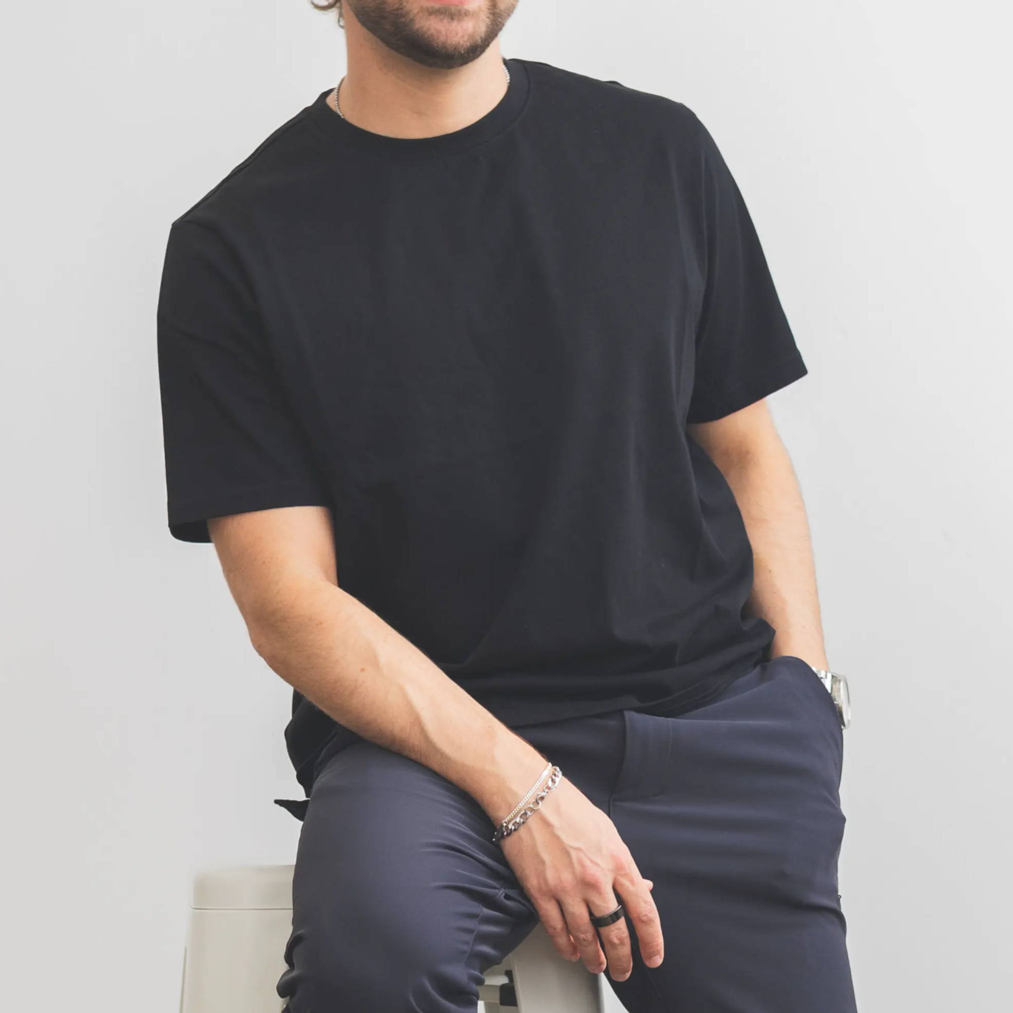 Person sitting on a stool, wearing a black shirt and dark pants.