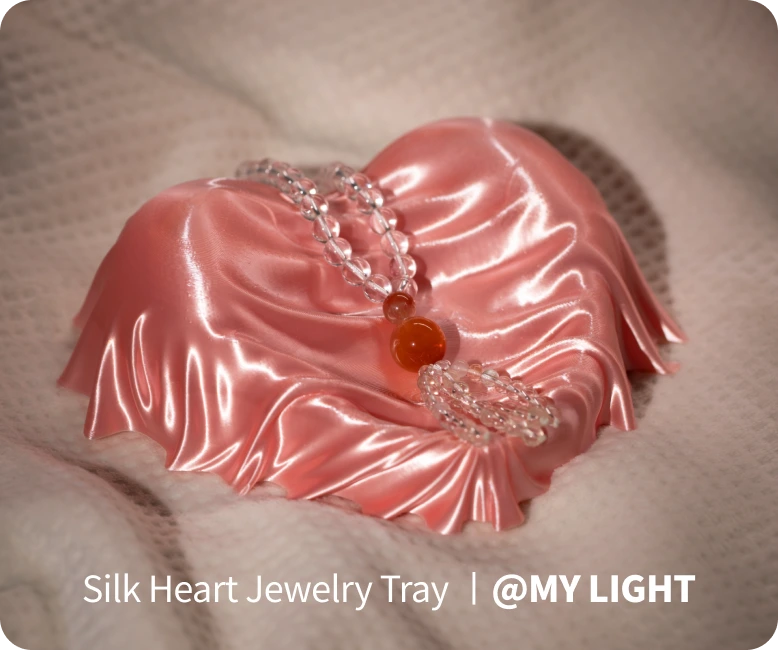 Silk heart-shaped jewelry tray with decorative elements on a soft background.