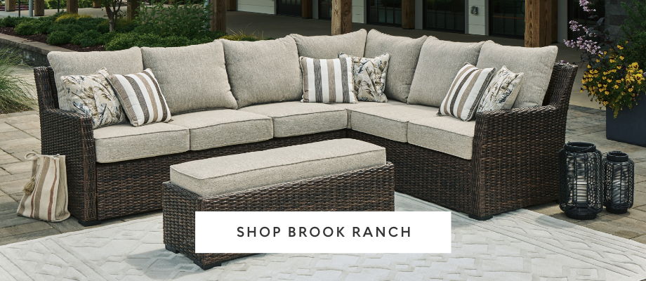 Outdoor sectional sofa with cushions and accent pillows, featuring a matching ottoman.